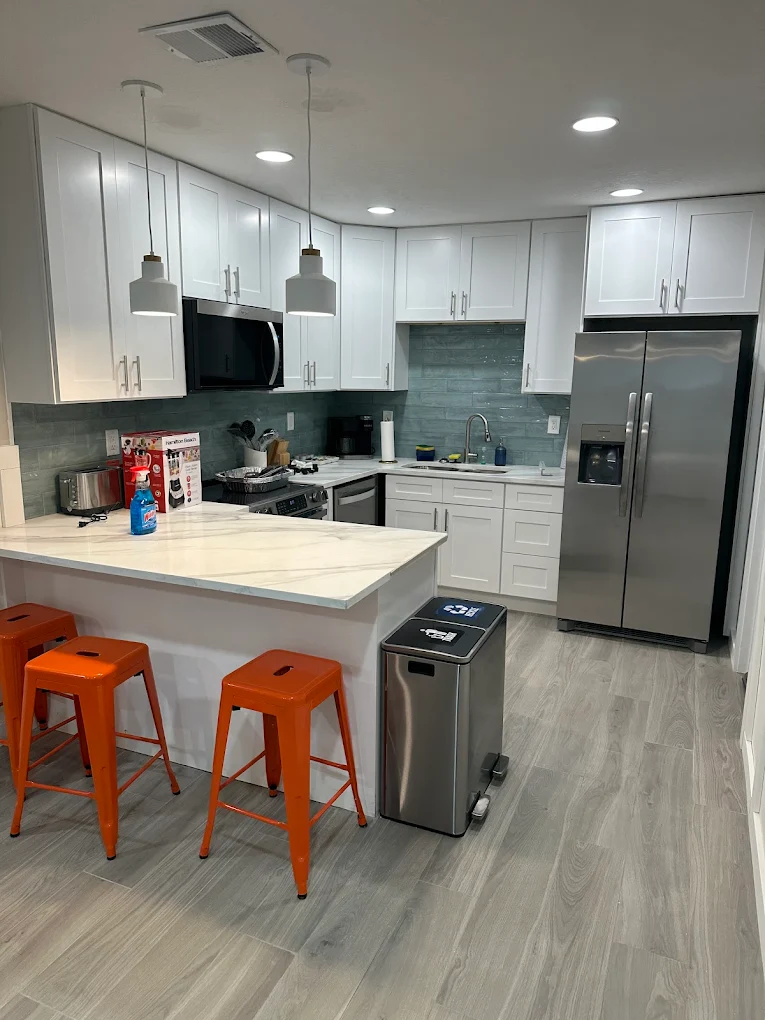 Modern white shaker kitchen remodel with quartz waterfall island and stainless appliances