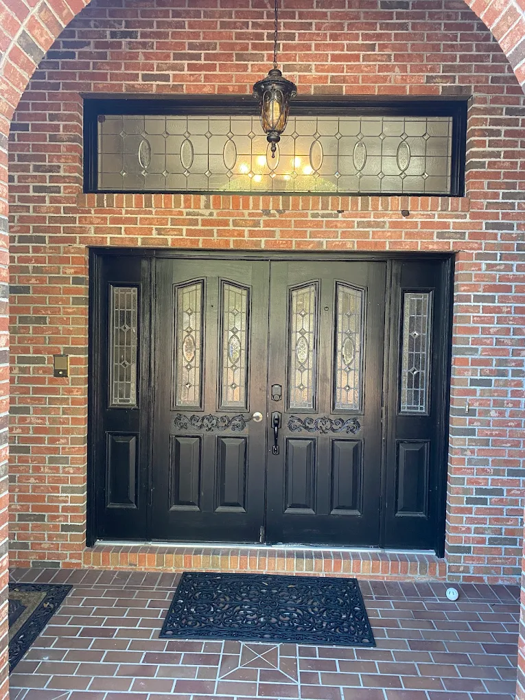 Custom black iron double front doors with leaded glass transom