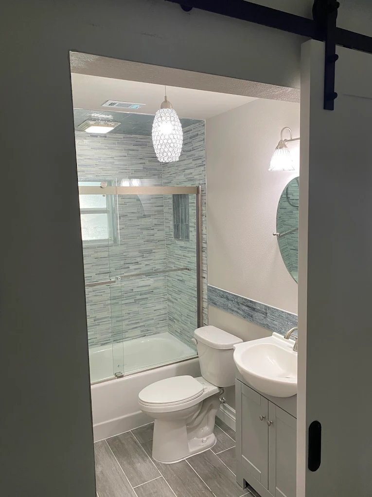Bathroom remodel with custom mosaic tile shower surround and barn door entry